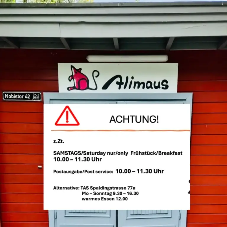 Das Bild zeigt ein Schild vor dem Eingang der Alimaus. Auf dem Schild ist ein Verkehrszeichen "Achtung" sichtbar. Text: "Zurzeit Samstags (Saturday) nur (only) Frühstück/Breakfast von 10 bis 11:30 Uhr. Postausgabe / Post service auch von 10 bis 11:30 Uhr. Alternative: TAS Spaldingstraße 77 a. Montag bis Sonntag von 9:30 bis 16:30 Uhr. Warmes Mittagessen um 12 Uhr."