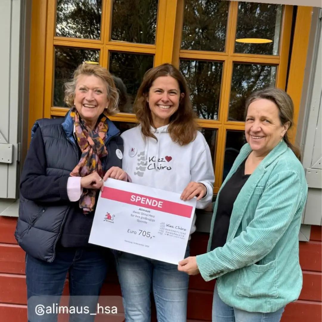 Drei Menschen schauen voller Freude in die Kamera. Alle drei halten einen symbolischen und übergroßen Scheck in ihren Händen. Auf dem Scheck ist zu erkennen: "Spende, 705 Euro".