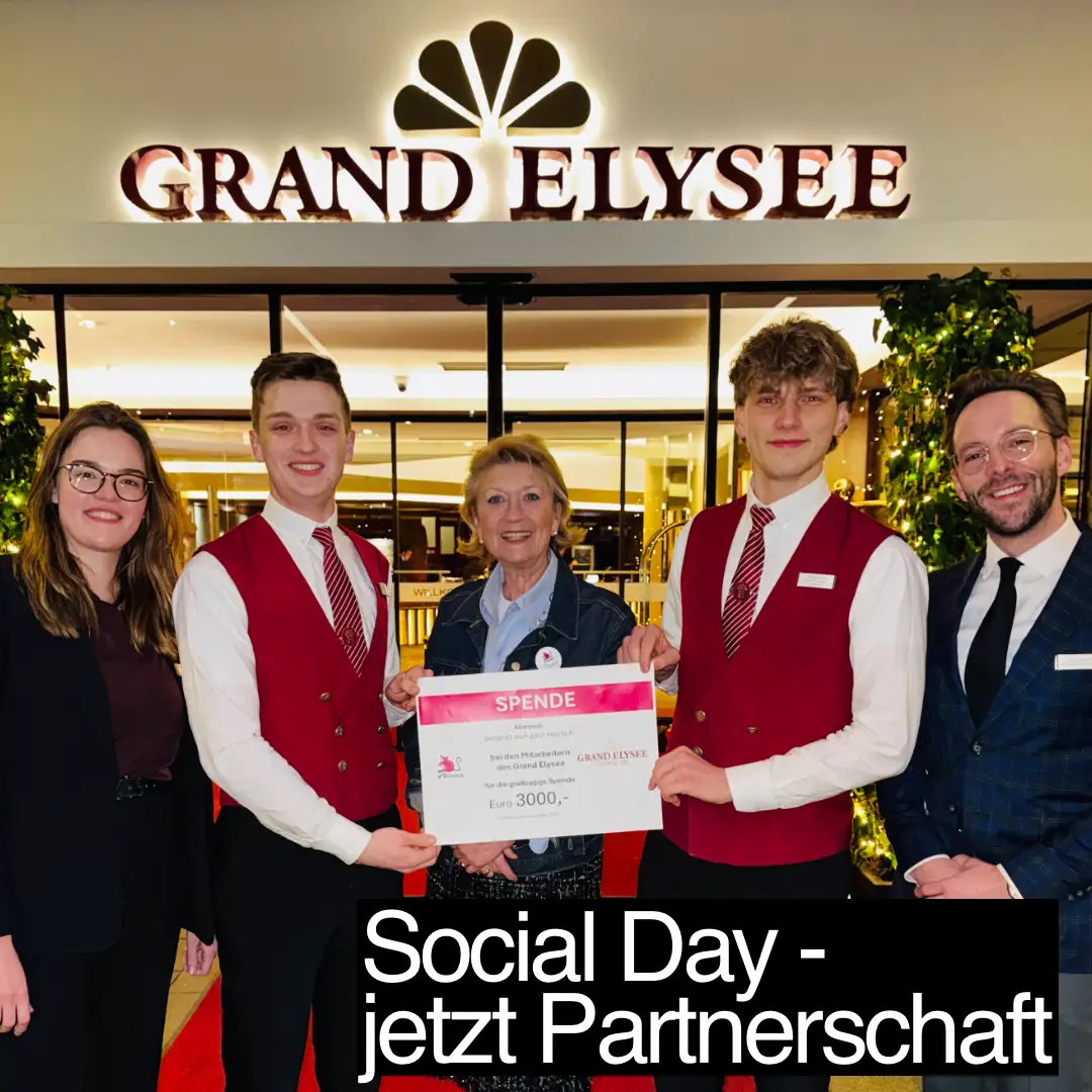 Das Bild zeigt fünf Menschen, die in einer Reihe stehen und die Kamera schauen. Die drei Personen in der Mitte halten einen symbolischen Scheck über 3000 Euro in der Hand. Im Hintergrund ist der Eingang mit dem Schriftzug des Hotels Grand Elysee sichtbar. Zusätzlicher Text: "Social Day - jetzt Partnerschaft".