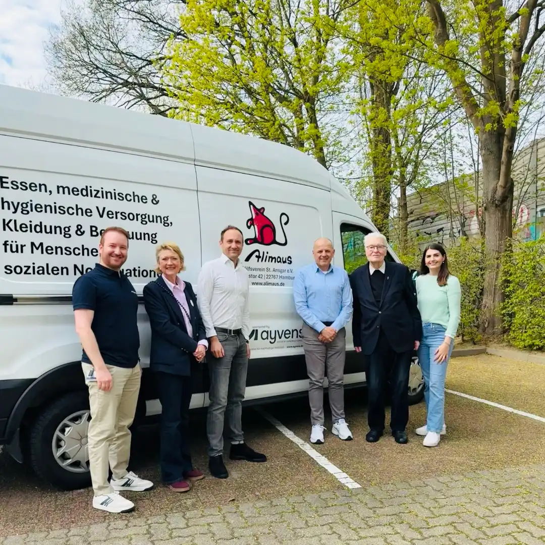 Das Bild zeigt den neuen Transporter der Alimaus. Vor dem Auto stehen sechs Menschen, die freundlich in die Kamera schauen.
