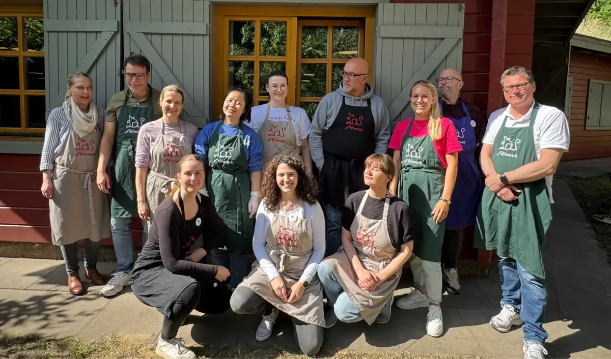 Das Bild zeigt eine Menschengruppe vor der Alimaus, die freundlich in die Kamera schauen.